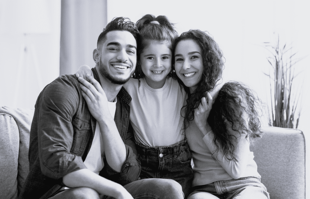 Familie af tre personer smiler sammen