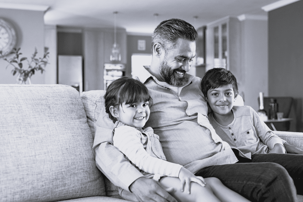 Familie smiler og sidder sammen