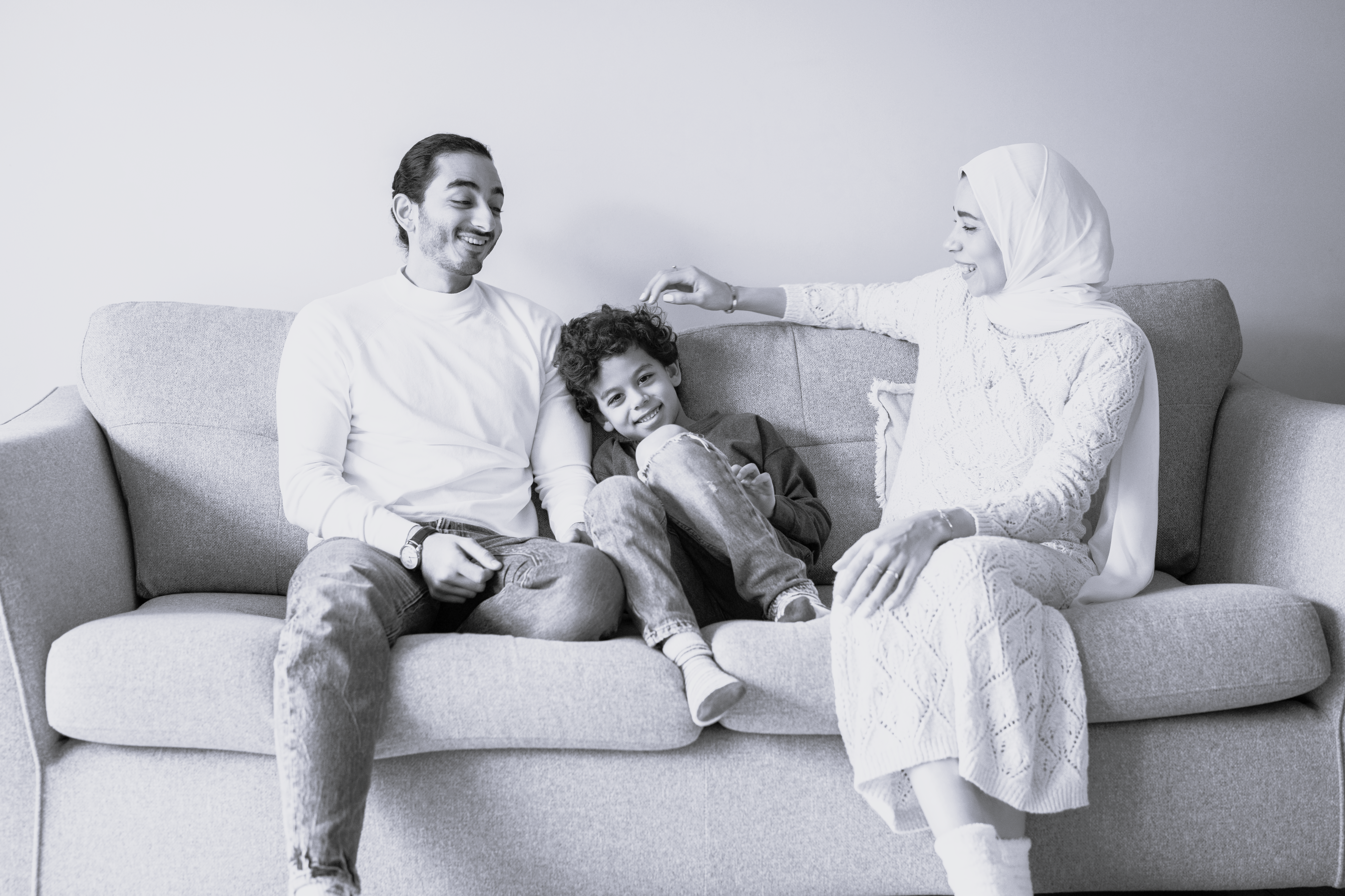 Familie sidder på sofa og smiler