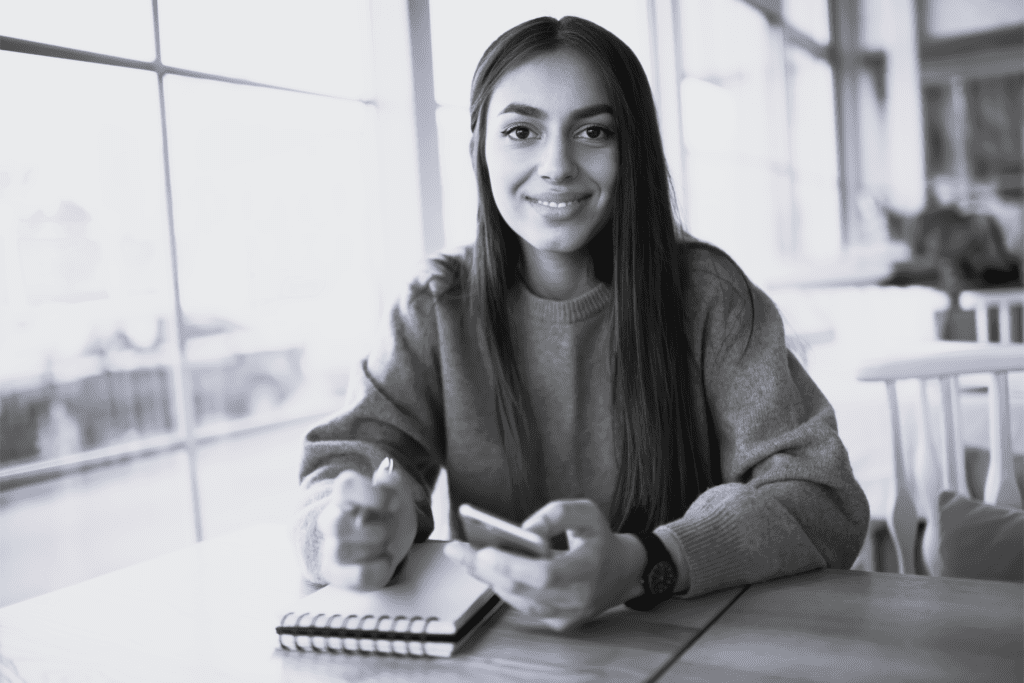 Ung pige skriver i notesblok og smiler