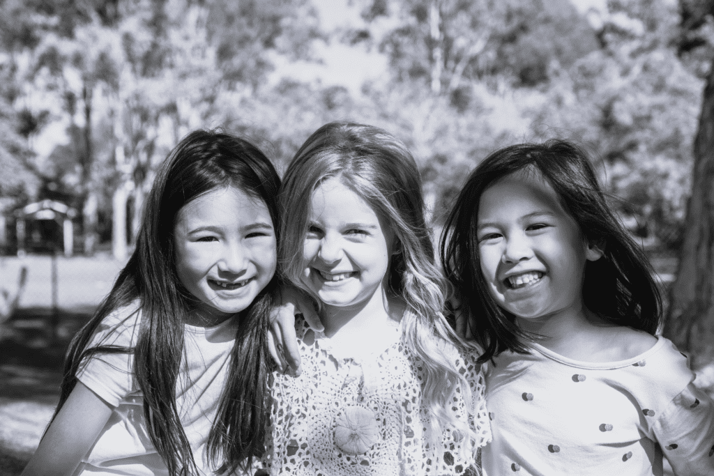 3 piger står sammen og smiler i naturen