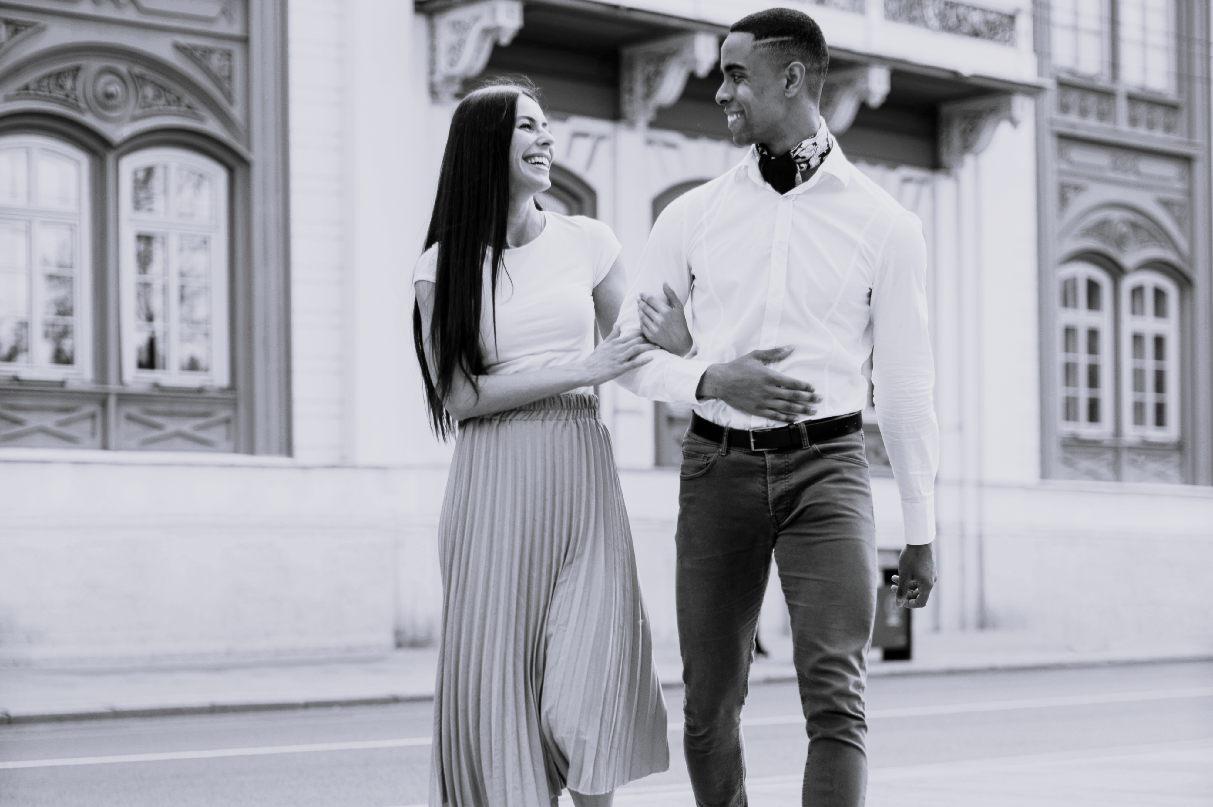 Multietnisk par smiler og går sammen på gaden i fint tøj