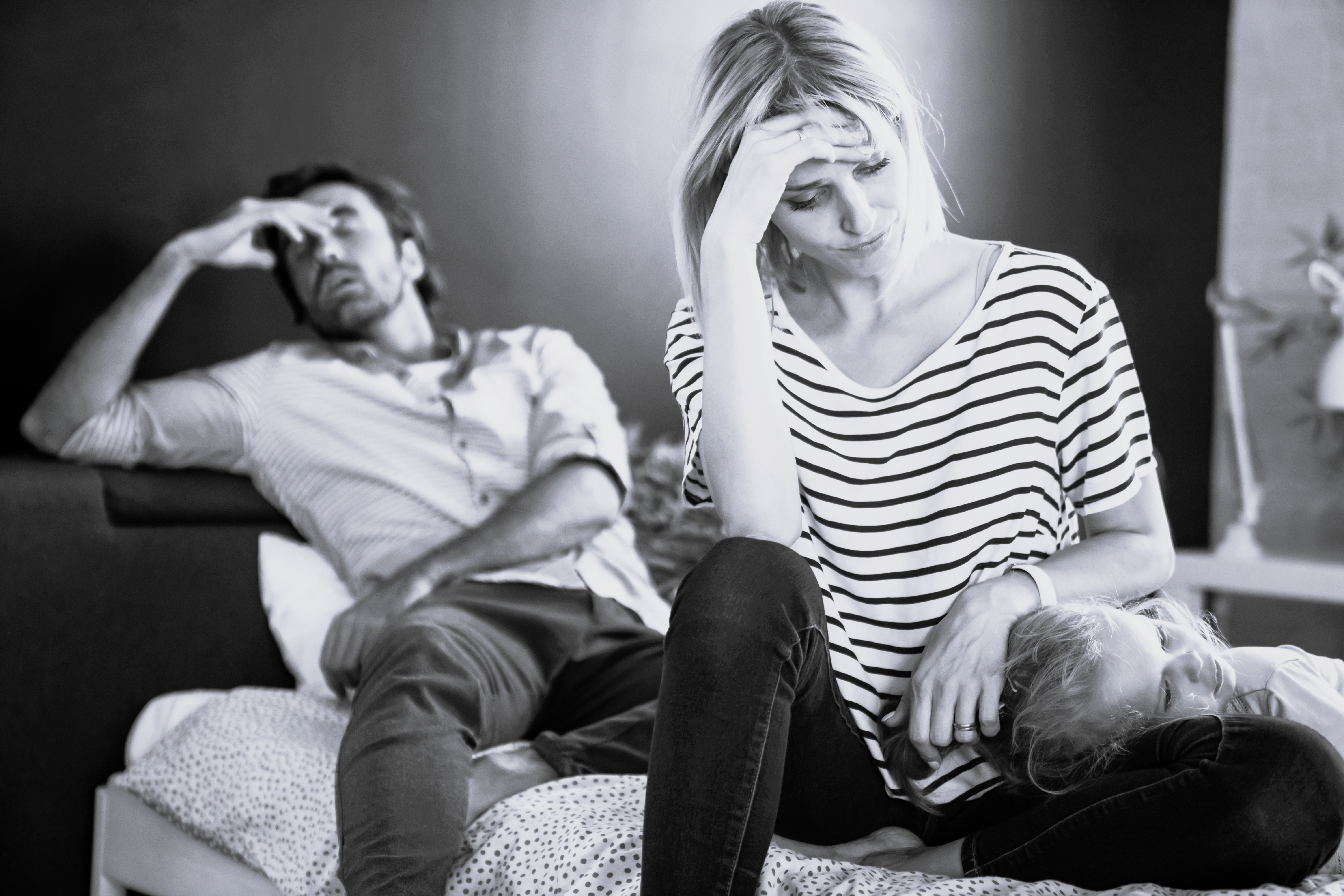 Nedtrykte forældre sidder på en seng med deres barn